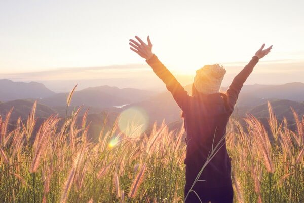 person spreading her arms wide while standing in a wheat field