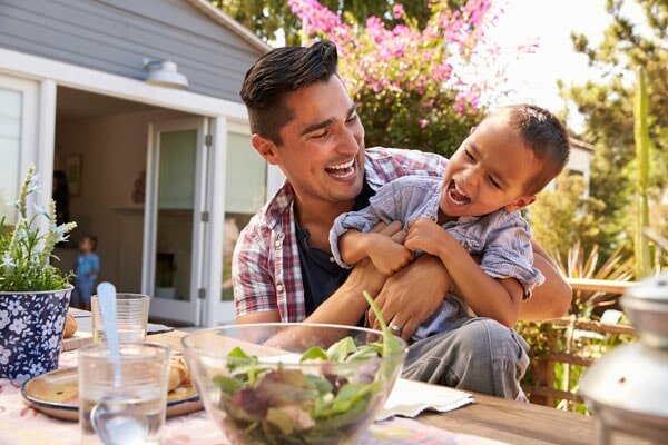 father playing with son outside while seated at a table