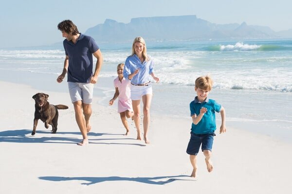 a father, mother, son, daughter and dog running on the beach