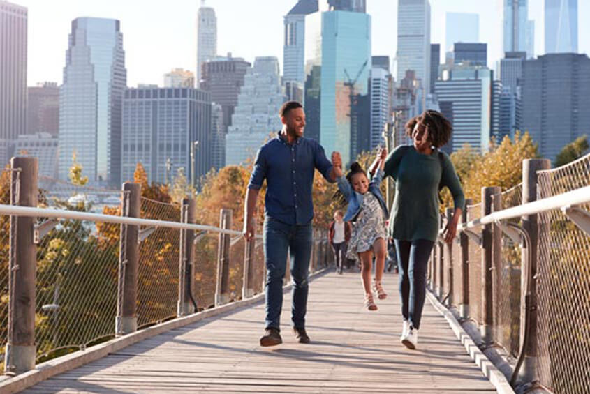 family walking through a park with a city behind them