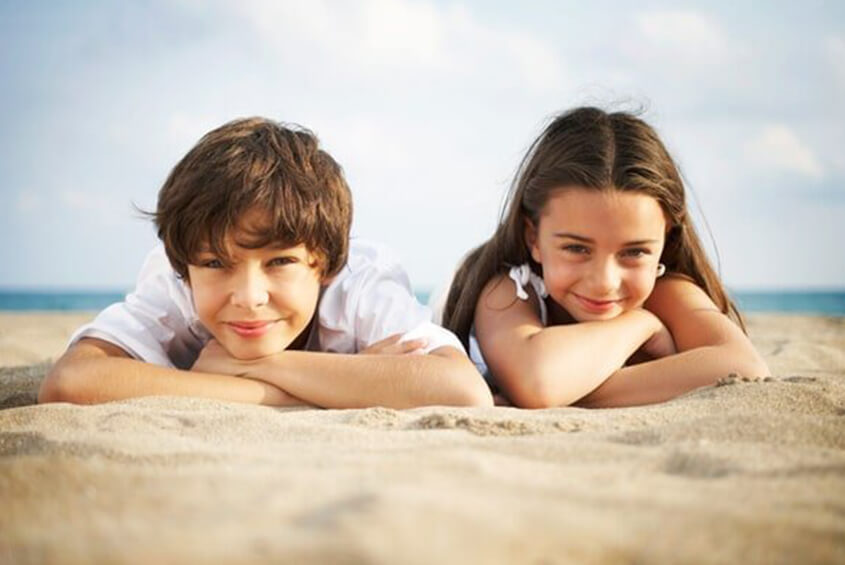 little boy and girl laying on the sand
