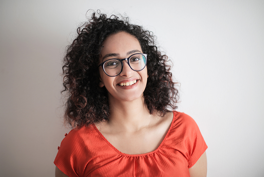 curly-haired woman with glasses smiling